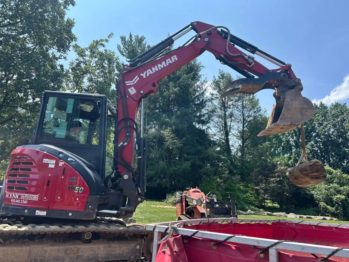 Excavator moving boulders for waterfall construction project